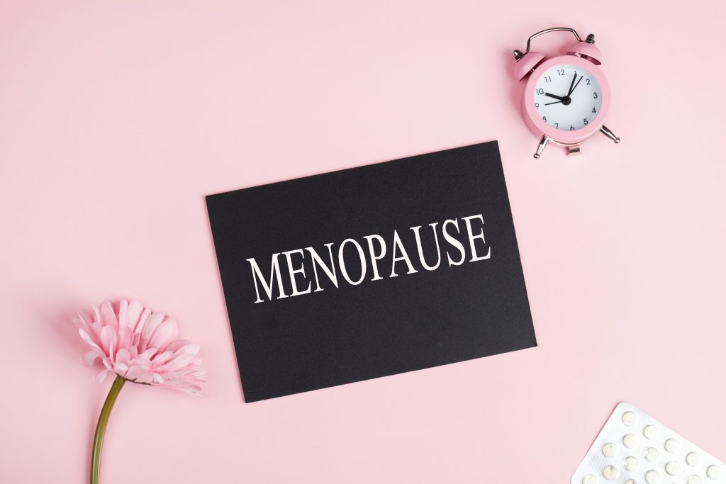 schwarzes Schild mit weißer Schrift "Menopause" auf rosa Hintergrund